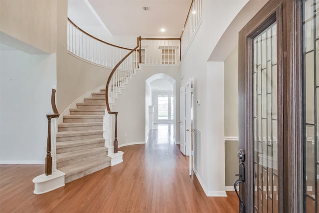 entryway featuring a towering ceiling and light hardwood / wood-style flooring