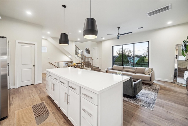 kitchen featuring light wood-type flooring, pendant lighting, white cabinets, a center island, and stainless steel refrigerator