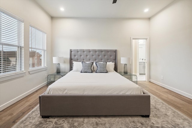 bedroom with connected bathroom, hardwood / wood-style flooring, and ceiling fan