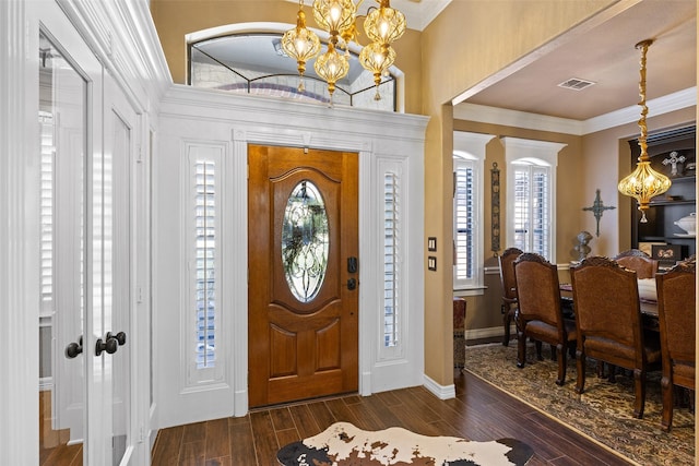 entrance foyer with dark hardwood / wood-style flooring, ornamental molding, and a notable chandelier