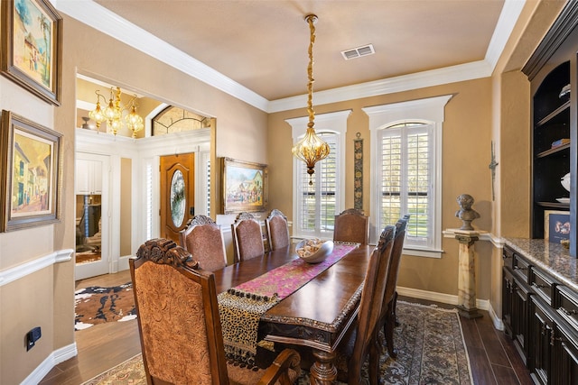 dining space featuring dark hardwood / wood-style flooring, ornamental molding, and a chandelier