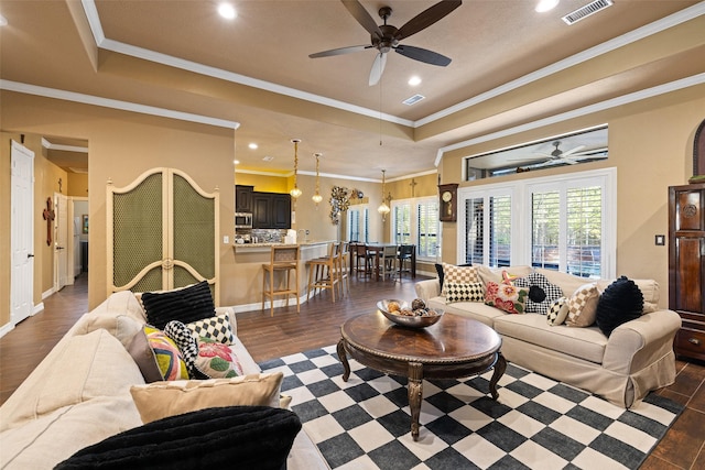 living room with a raised ceiling, ceiling fan, dark wood-type flooring, and crown molding