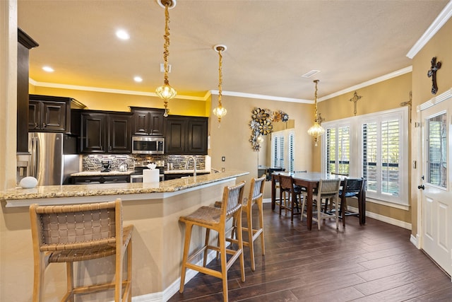 kitchen with a kitchen bar, decorative light fixtures, and appliances with stainless steel finishes