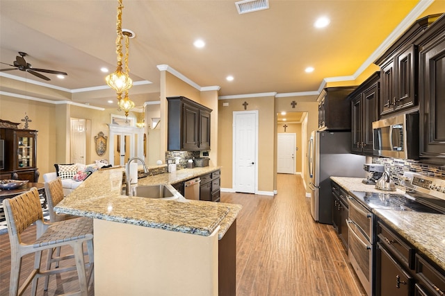 kitchen featuring ceiling fan, sink, a kitchen breakfast bar, pendant lighting, and appliances with stainless steel finishes