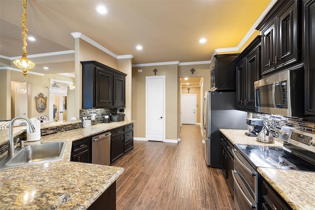 kitchen with decorative backsplash, appliances with stainless steel finishes, ornamental molding, sink, and decorative light fixtures