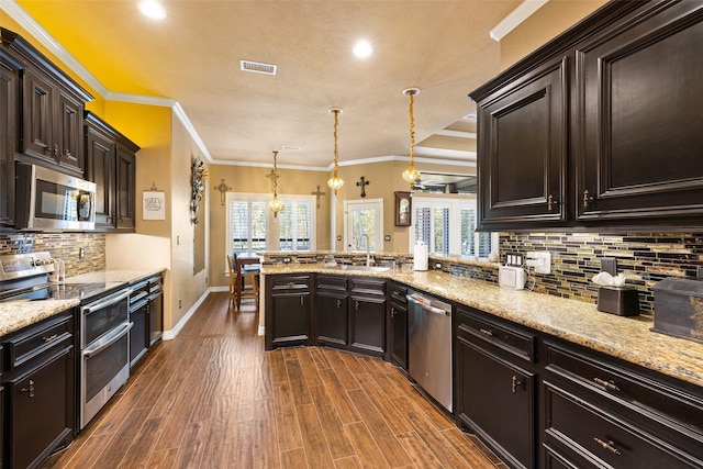 kitchen with an inviting chandelier, sink, appliances with stainless steel finishes, decorative light fixtures, and kitchen peninsula