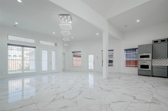 unfurnished living room featuring a towering ceiling and a notable chandelier