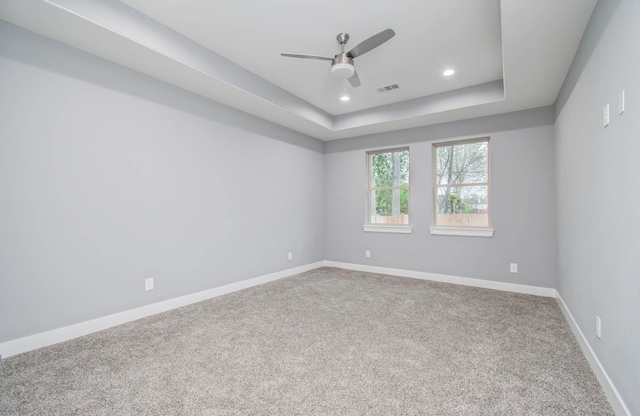 unfurnished room featuring ceiling fan, carpet floors, and a tray ceiling