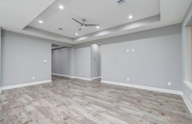 spare room featuring light hardwood / wood-style flooring, a raised ceiling, and ceiling fan