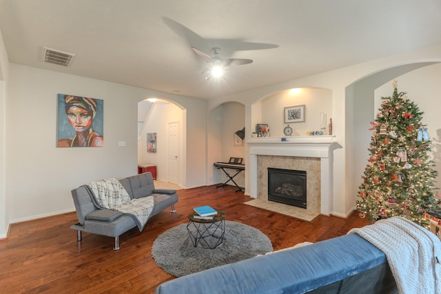 living room featuring ceiling fan, a fireplace, and wood-type flooring