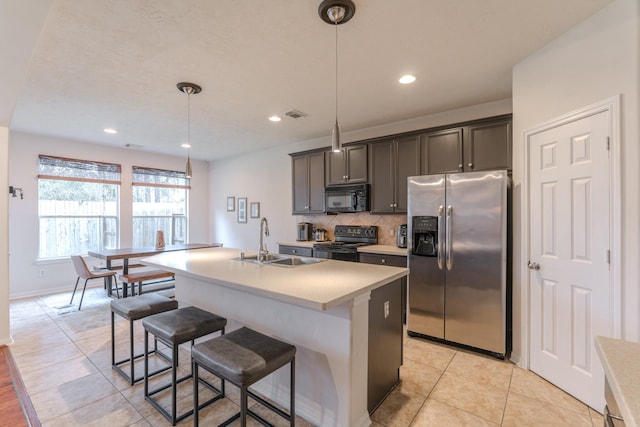 kitchen featuring a kitchen island with sink, black appliances, sink, light tile patterned floors, and decorative light fixtures