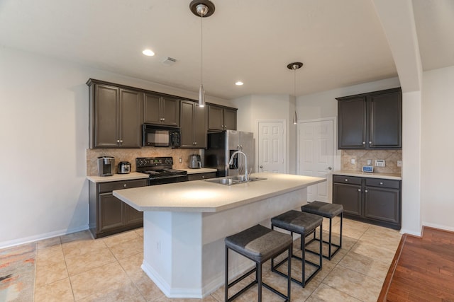 kitchen featuring black appliances, a center island with sink, sink, hanging light fixtures, and light tile patterned floors