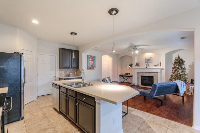 kitchen featuring stainless steel appliances, ceiling fan, sink, light tile patterned floors, and a center island with sink