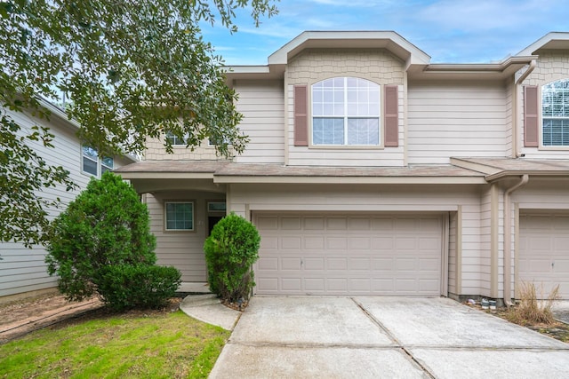 multi unit property featuring a garage, driveway, and a shingled roof