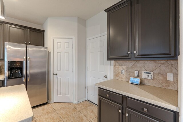 kitchen featuring decorative backsplash, light tile patterned flooring, dark brown cabinetry, and stainless steel refrigerator with ice dispenser