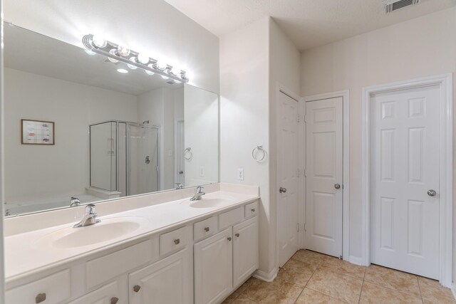 bathroom with tile patterned floors, vanity, a textured ceiling, and walk in shower