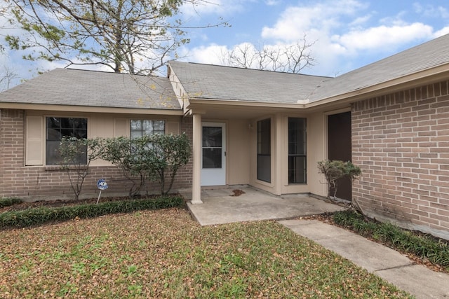 property entrance with a lawn and a patio