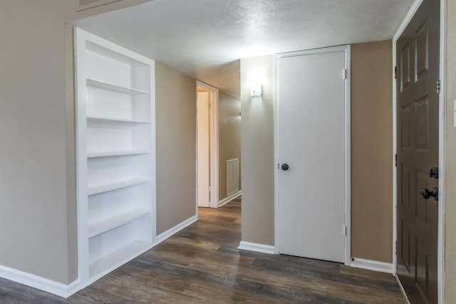 hallway with dark hardwood / wood-style flooring, built in features, and a textured ceiling