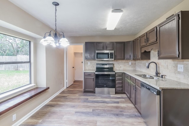 kitchen featuring sink, hanging light fixtures, an inviting chandelier, tasteful backsplash, and appliances with stainless steel finishes