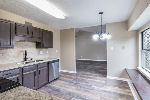 kitchen featuring light stone countertops, dishwasher, sink, hanging light fixtures, and a chandelier