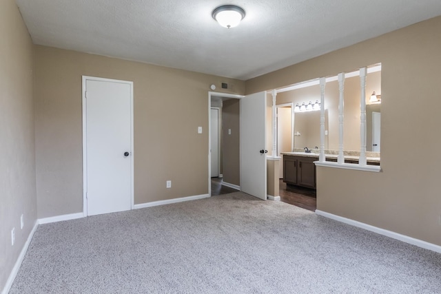 unfurnished bedroom featuring carpet floors, sink, connected bathroom, and a closet