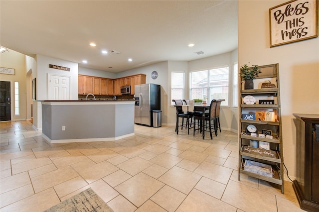 kitchen featuring a kitchen breakfast bar, light tile patterned floors, sink, and appliances with stainless steel finishes