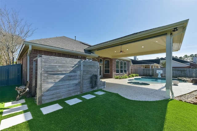 back of property with ceiling fan, a fenced in pool, a yard, and a patio