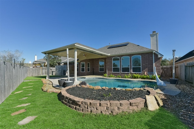 back of house featuring ceiling fan, a patio, solar panels, a yard, and a fenced in pool