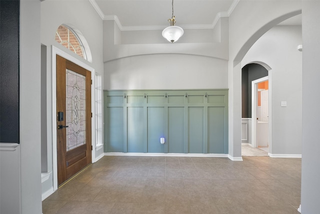 foyer with ornamental molding and a towering ceiling