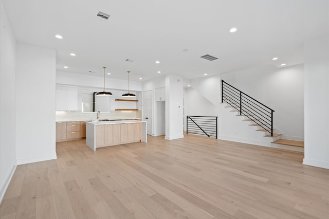 unfurnished living room with sink and light hardwood / wood-style flooring