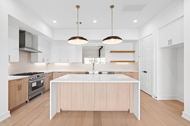 kitchen with white cabinetry, wall chimney exhaust hood, high end stainless steel range oven, and a kitchen island