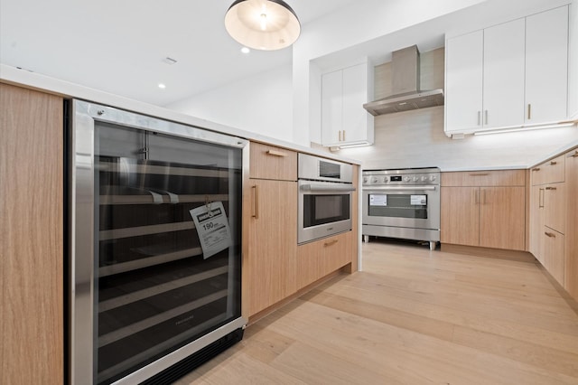 kitchen featuring wine cooler, white cabinets, wall chimney range hood, and appliances with stainless steel finishes