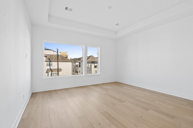 spare room featuring light hardwood / wood-style flooring and a tray ceiling