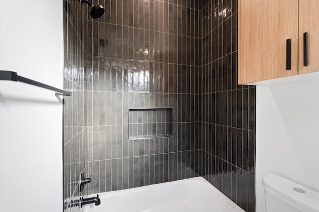 bathroom with toilet and tiled shower / bath