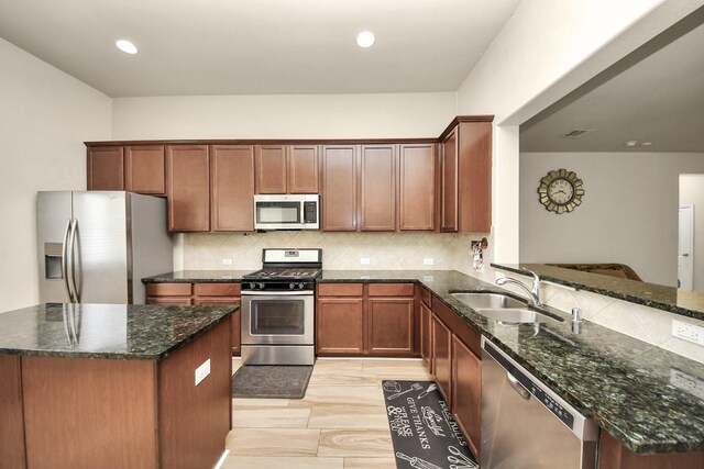 kitchen featuring kitchen peninsula, dark stone countertops, sink, and stainless steel appliances