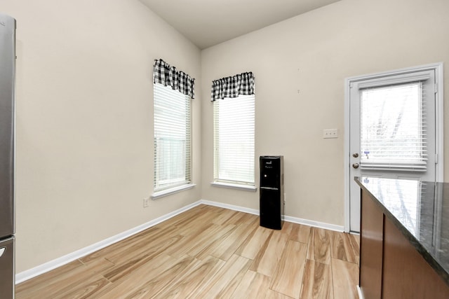 kitchen with a healthy amount of sunlight, dark stone countertops, and light hardwood / wood-style floors