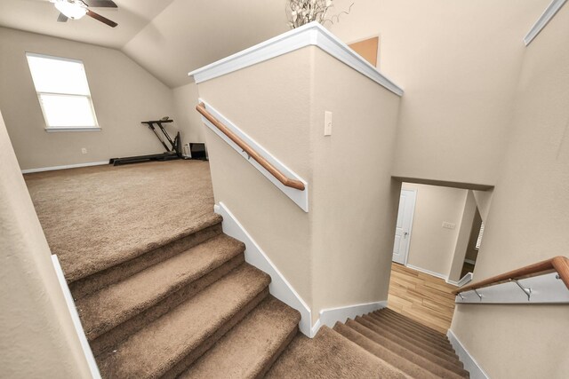 stairway featuring ceiling fan, wood-type flooring, and vaulted ceiling