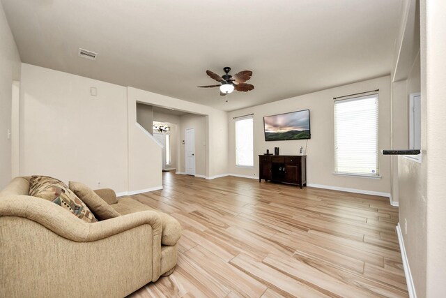 living room featuring ceiling fan with notable chandelier and wood-type flooring