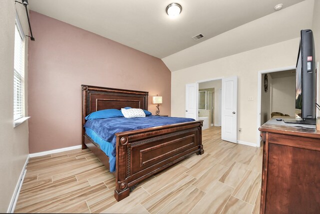 bedroom with ensuite bath and lofted ceiling