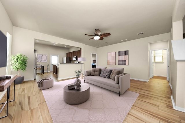 living room featuring light hardwood / wood-style flooring and ceiling fan