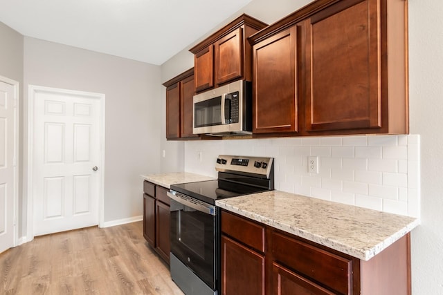 kitchen with light stone countertops, light hardwood / wood-style floors, and appliances with stainless steel finishes