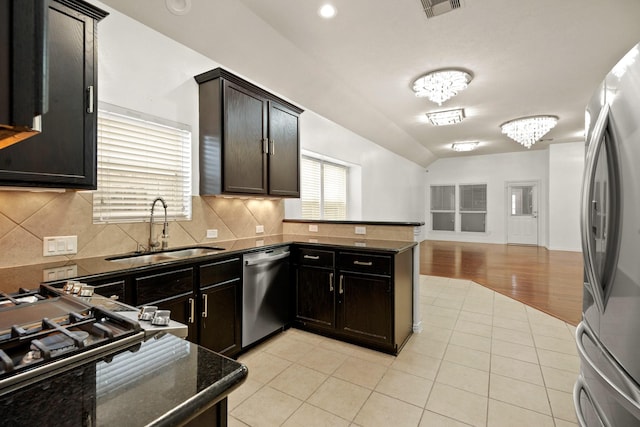 kitchen featuring dark brown cabinetry, sink, stainless steel appliances, a chandelier, and light tile patterned floors