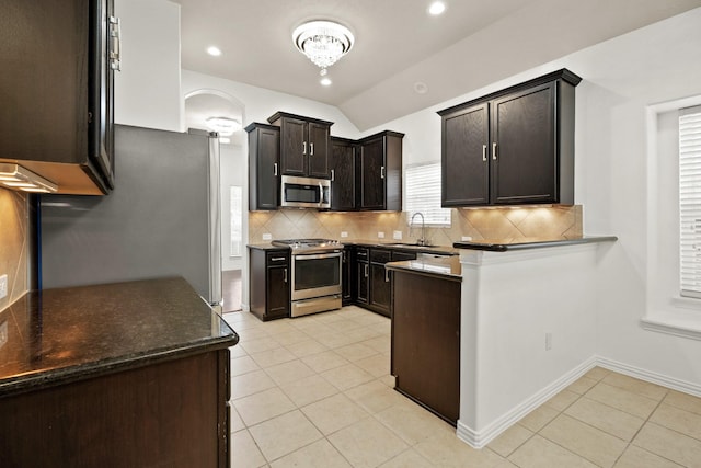 kitchen with tasteful backsplash, stainless steel appliances, vaulted ceiling, sink, and light tile patterned floors