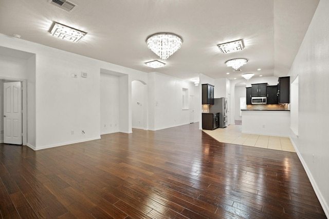 unfurnished living room featuring dark hardwood / wood-style floors and an inviting chandelier