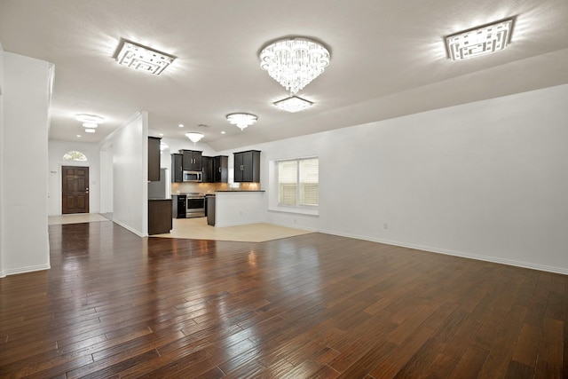 unfurnished living room featuring dark wood-type flooring and a notable chandelier