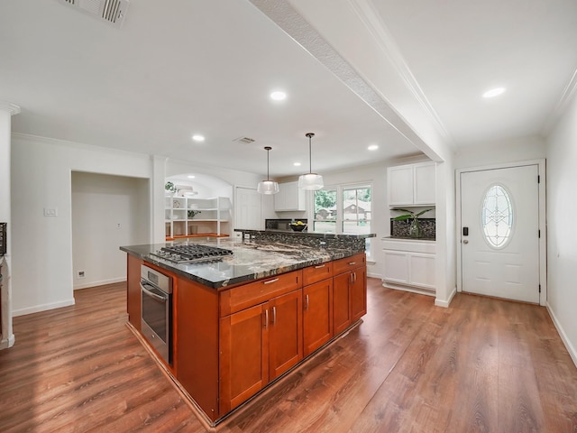 kitchen featuring a center island, pendant lighting, dark stone counters, white cabinets, and appliances with stainless steel finishes