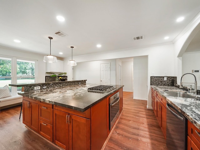 kitchen featuring appliances with stainless steel finishes, hardwood / wood-style flooring, hanging light fixtures, and sink