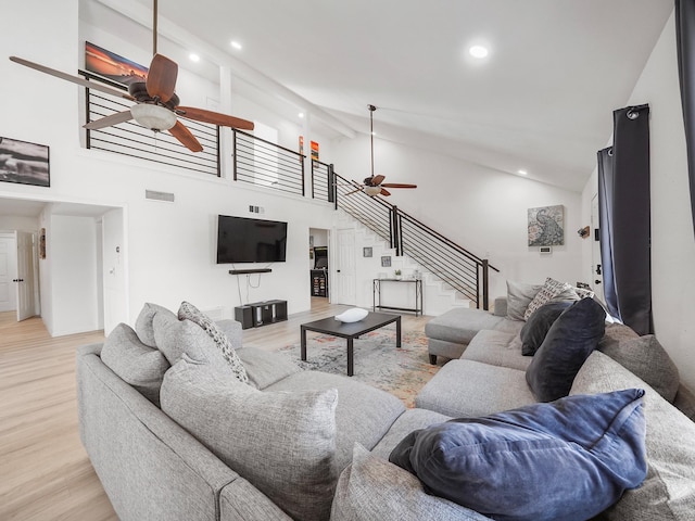 living room with ceiling fan, light hardwood / wood-style floors, and high vaulted ceiling