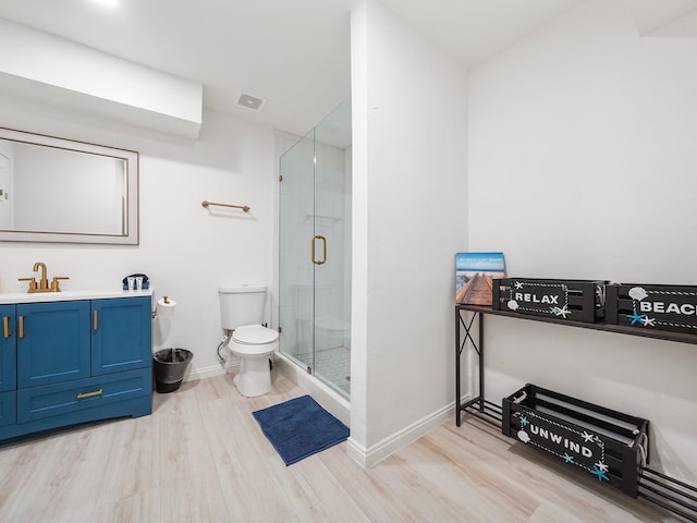 bathroom featuring hardwood / wood-style floors, vanity, toilet, and a shower with shower door