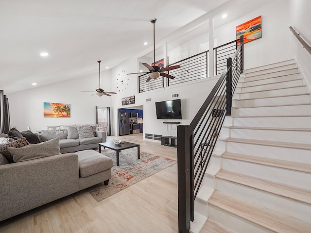 living room with ceiling fan, high vaulted ceiling, and light hardwood / wood-style flooring